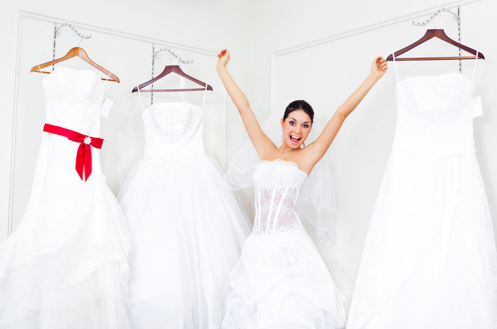 Pretty young excited woman is choosing a wedding dress in the shop