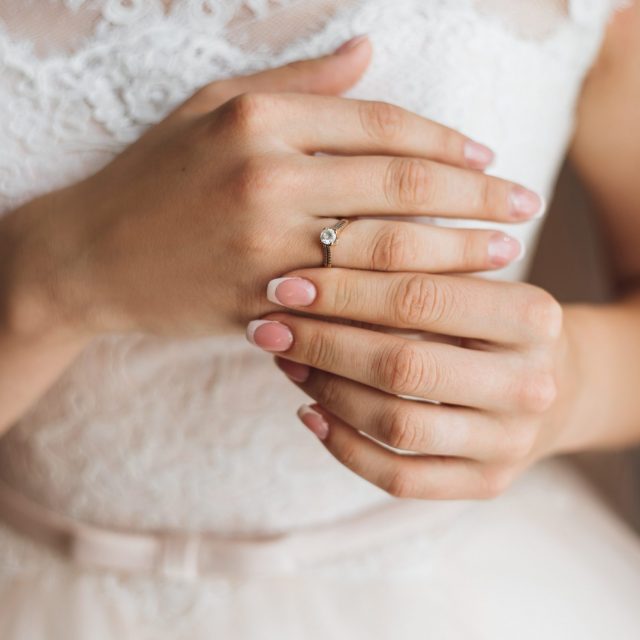 Hands of a bride with tender french manicure and precious engage