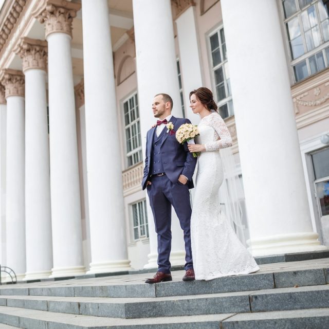 loving couple of newlyweds walks in the old city near columns in