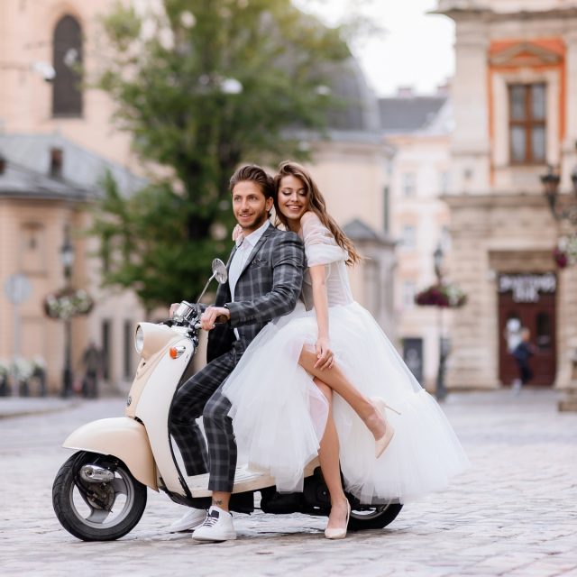 Bride and groom posing on vintage motor scooter